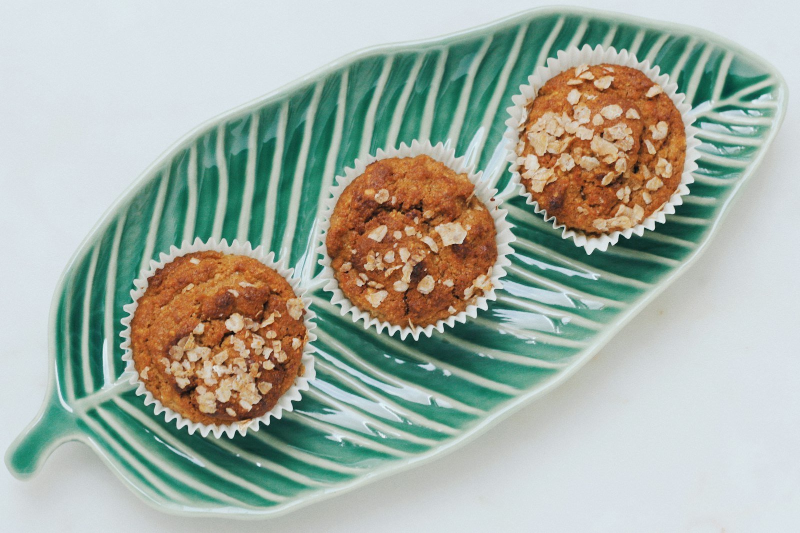Scooping the oat batter into a greased muffin tin before topping with fresh blueberries