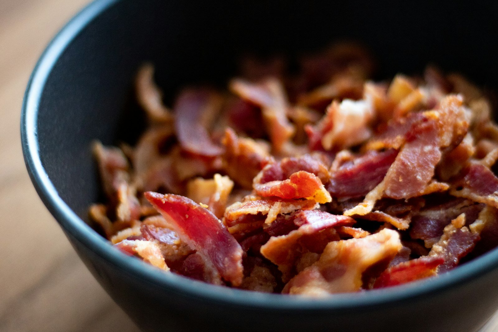 A tortilla chip scooping a stretchy, cheesy bite of baked bacon ranch dip with crumbled bacon on top