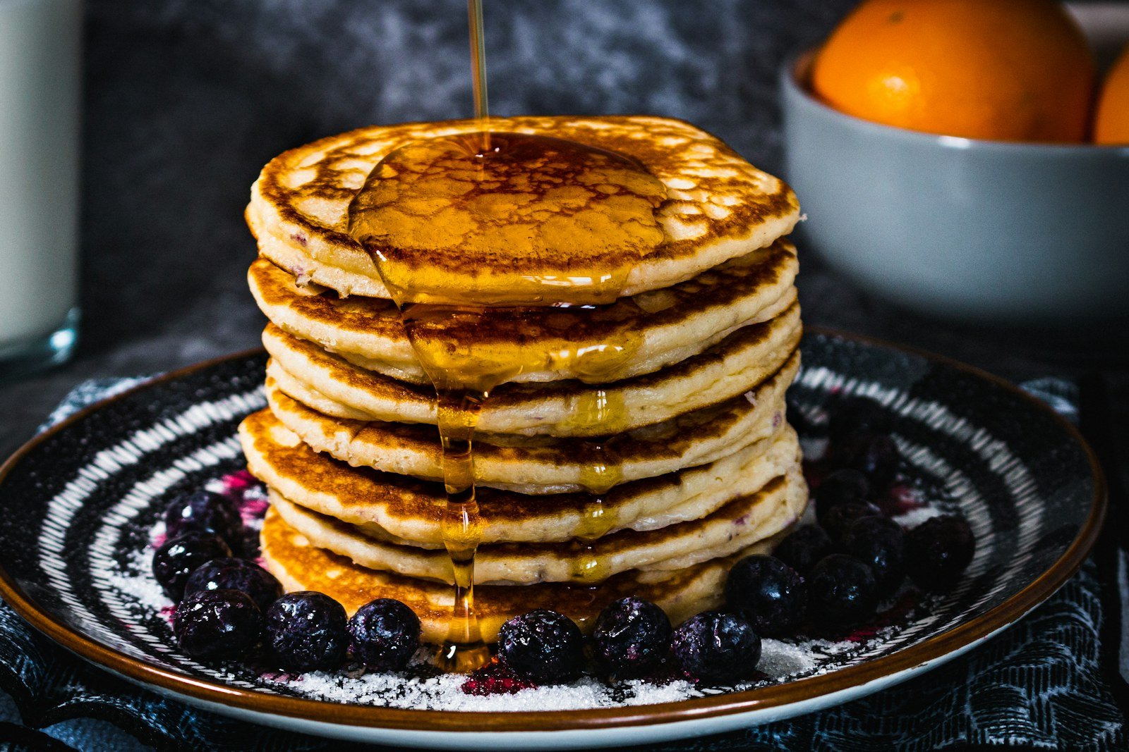 Golden buttermilk pancakes stacked high with syrup dripping down the sides