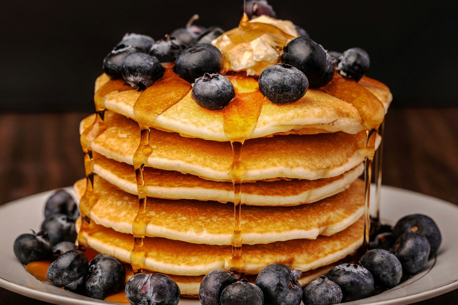 Tall stack of fluffy buttermilk pancakes topped with blueberries and maple syrup