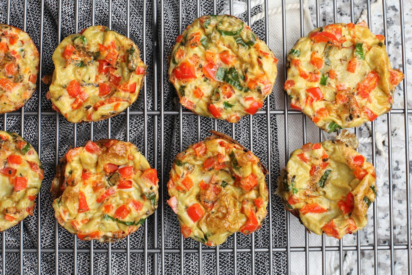 High protein breakfast egg bites with spinach, red pepper and cheese on a cooling rack