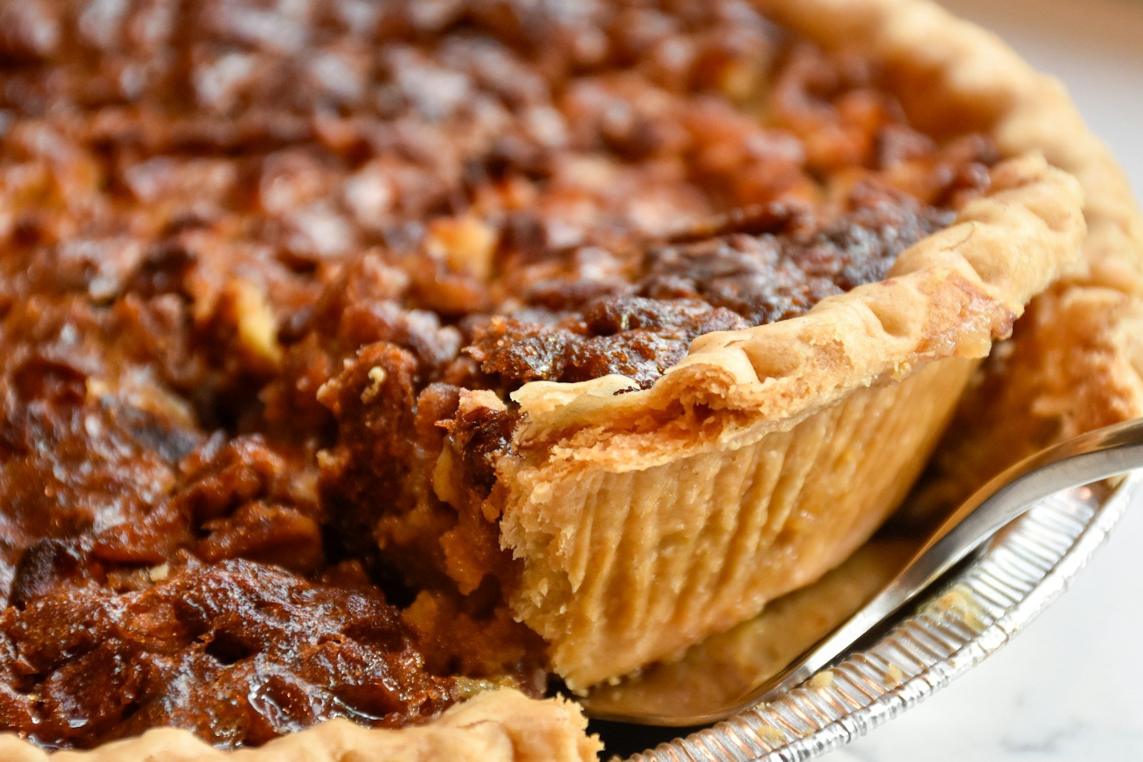 A classic pecan pie with a glossy caramel filling and toasted pecan halves, ready to slice for Thanksgiving