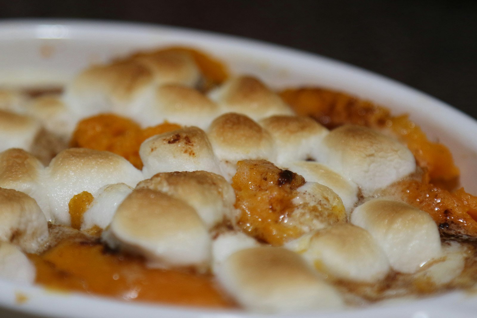 Sweet potato casserole with golden toasted marshmallows on one half and crunchy pecan streusel on the other in a white baking dish