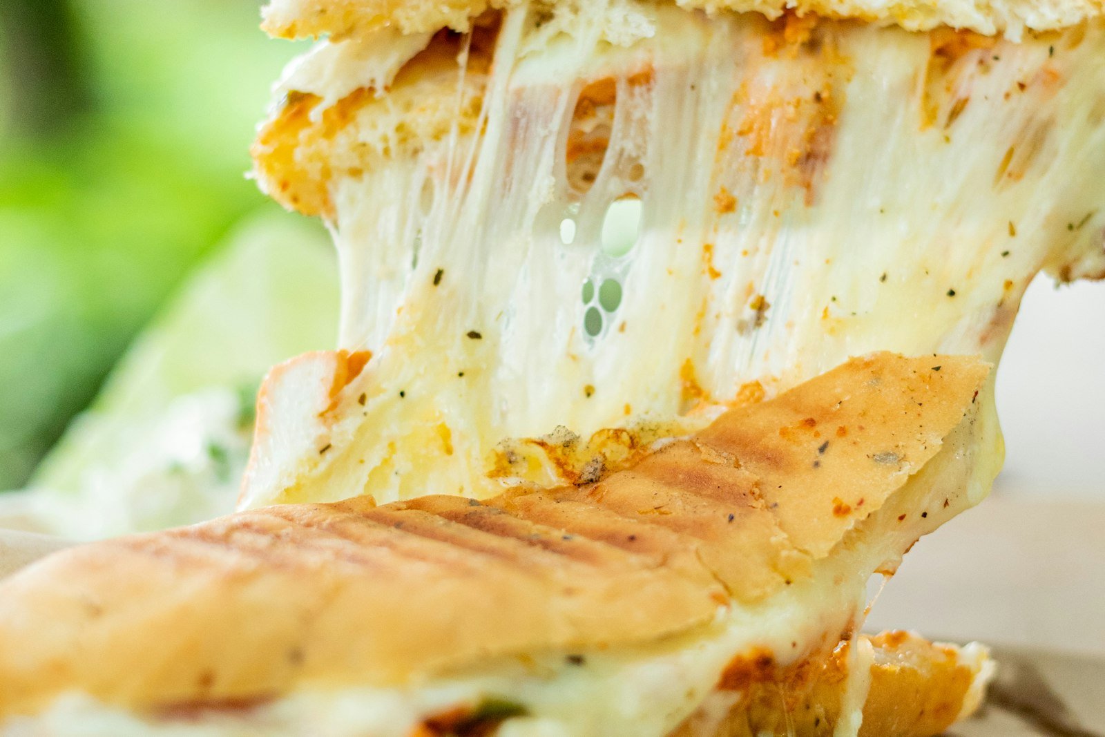 A golden sourdough apple cheddar grilled cheese cut in half, showing melted cheese and thin apple slices with a honey drizzle
