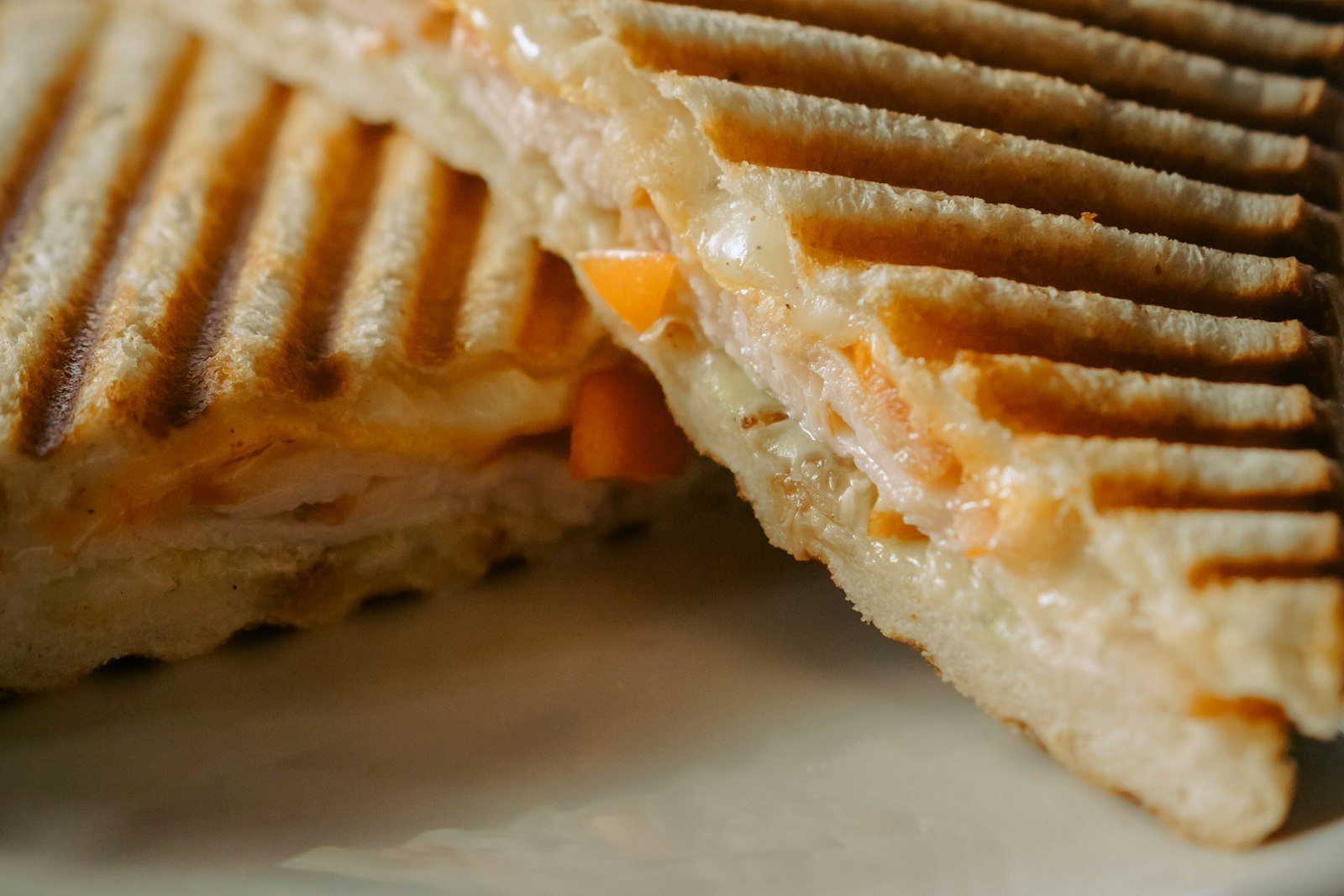 A halved apple cheddar grilled cheese pulling apart with melted cheese, apple slices and a honey drizzle