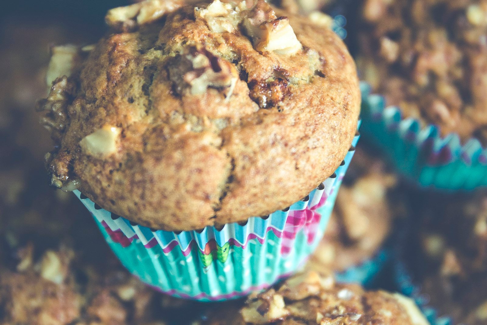A batch of golden banana protein muffins on a cooling rack, one split open to show the soft, moist crumb