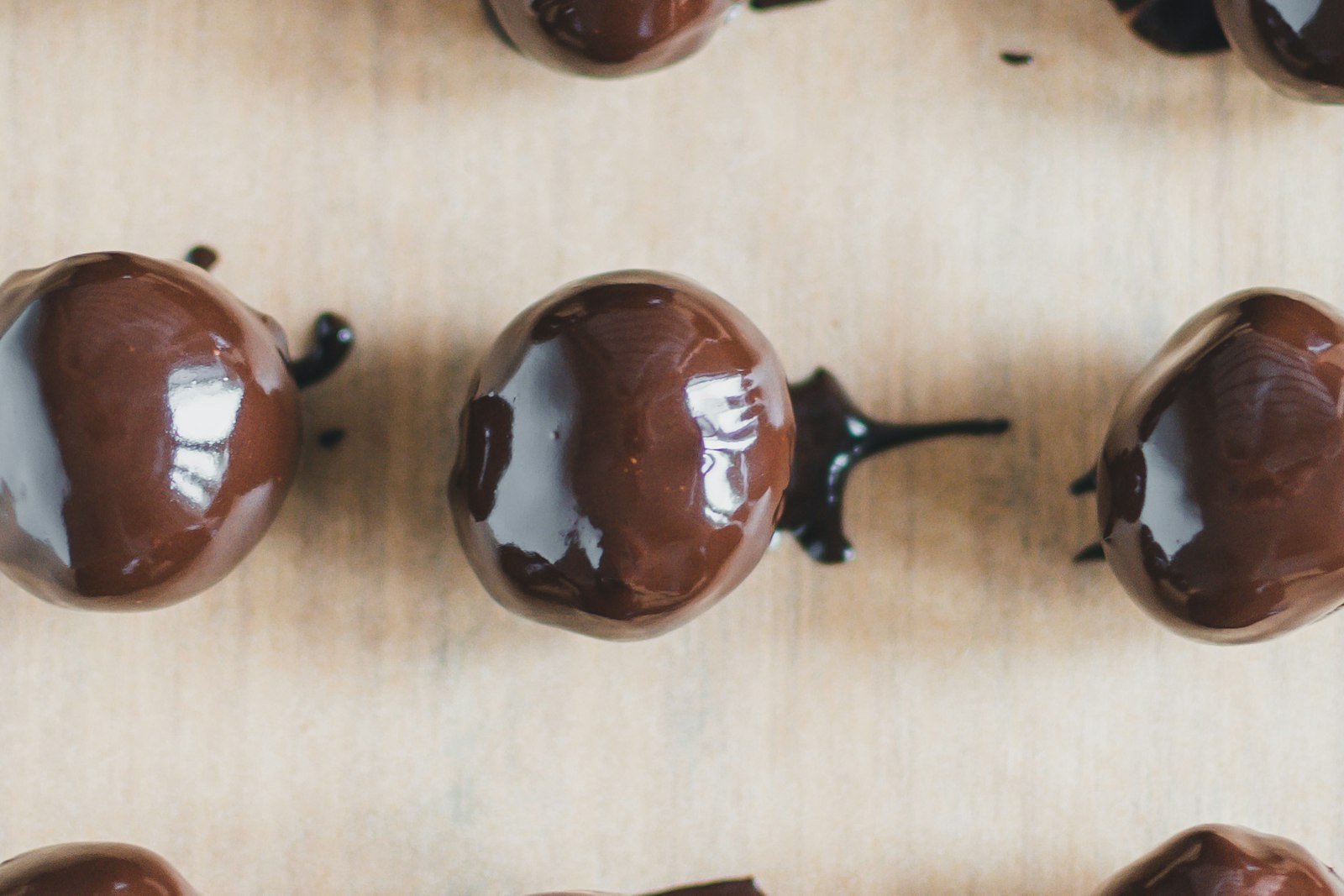 Rows of homemade buckeyes, creamy peanut butter balls dipped in glossy dark chocolate with a round patch of peanut butter showing on top, on a parchment-lined tray