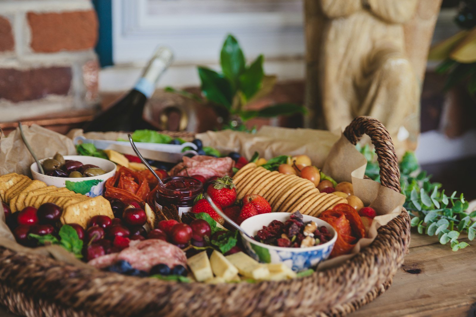 A round Christmas charcuterie wreath with cheeses, salami, grapes, cranberries and rosemary sprigs on a wooden board