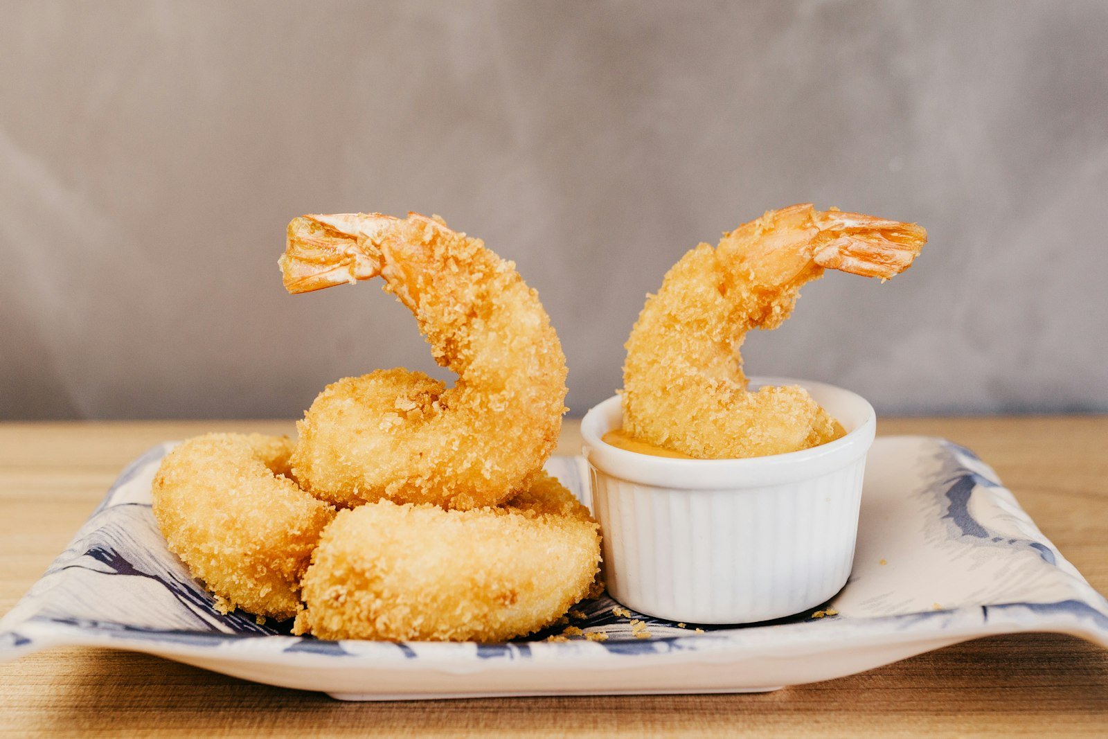 Coconut shrimp being dipped into a small bowl of orange chili sauce, showing the crunchy coconut crust and a juicy pink shrimp inside