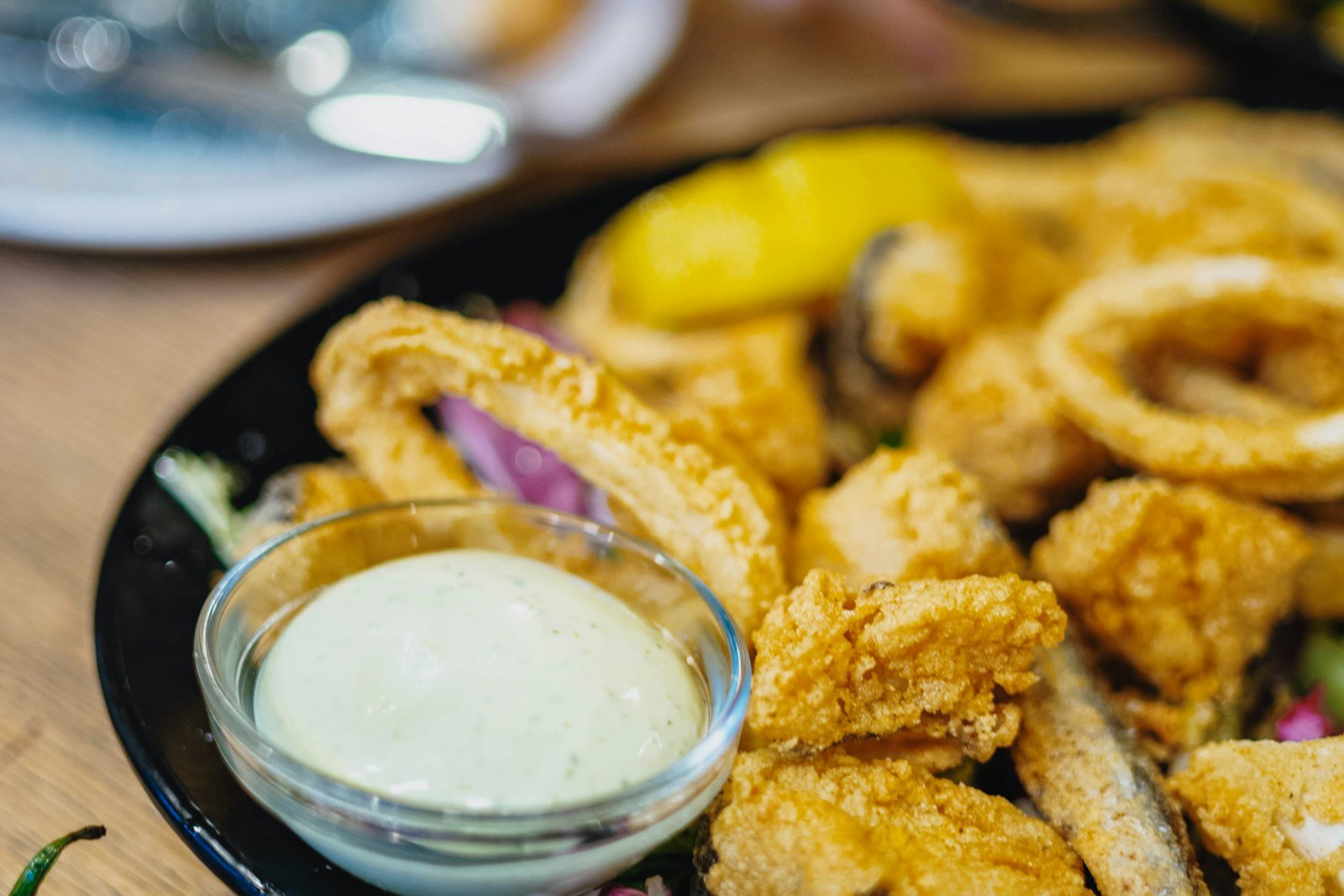 Golden calamari rings being lifted from hot oil with a spider strainer over a heavy Dutch oven