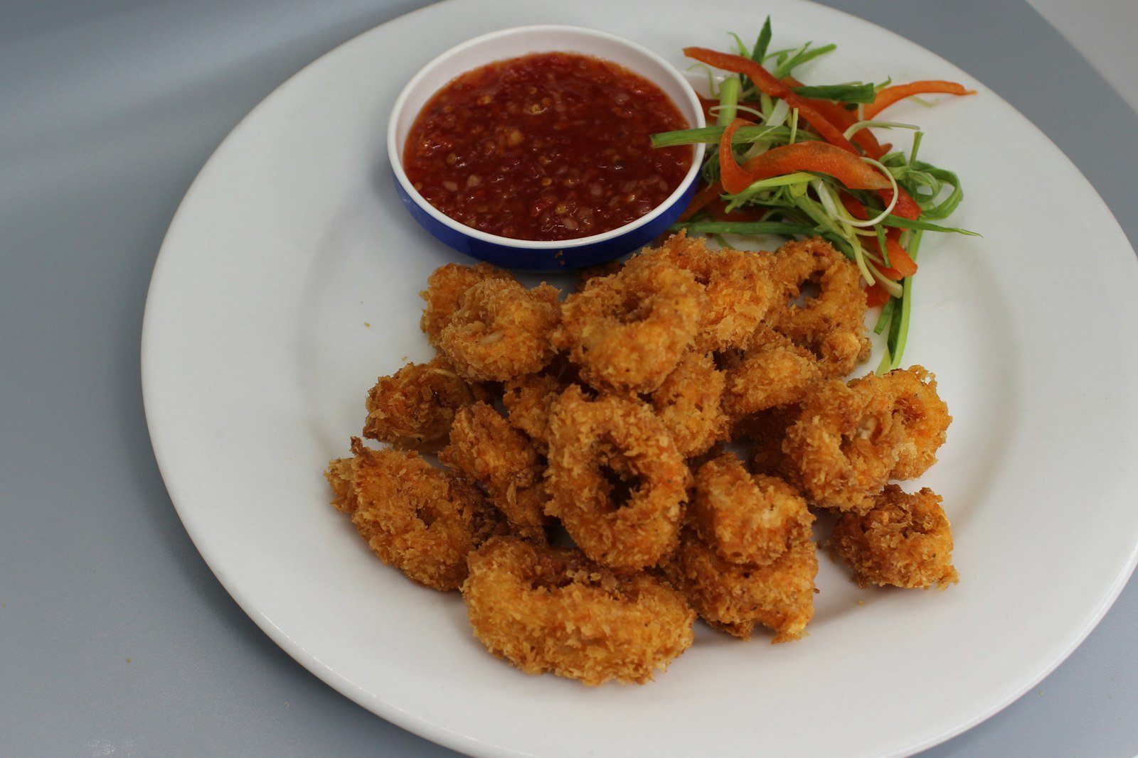 A heaping platter of golden fried calamari rings and tentacles with lemon wedges, parsley and a bowl of warm marinara