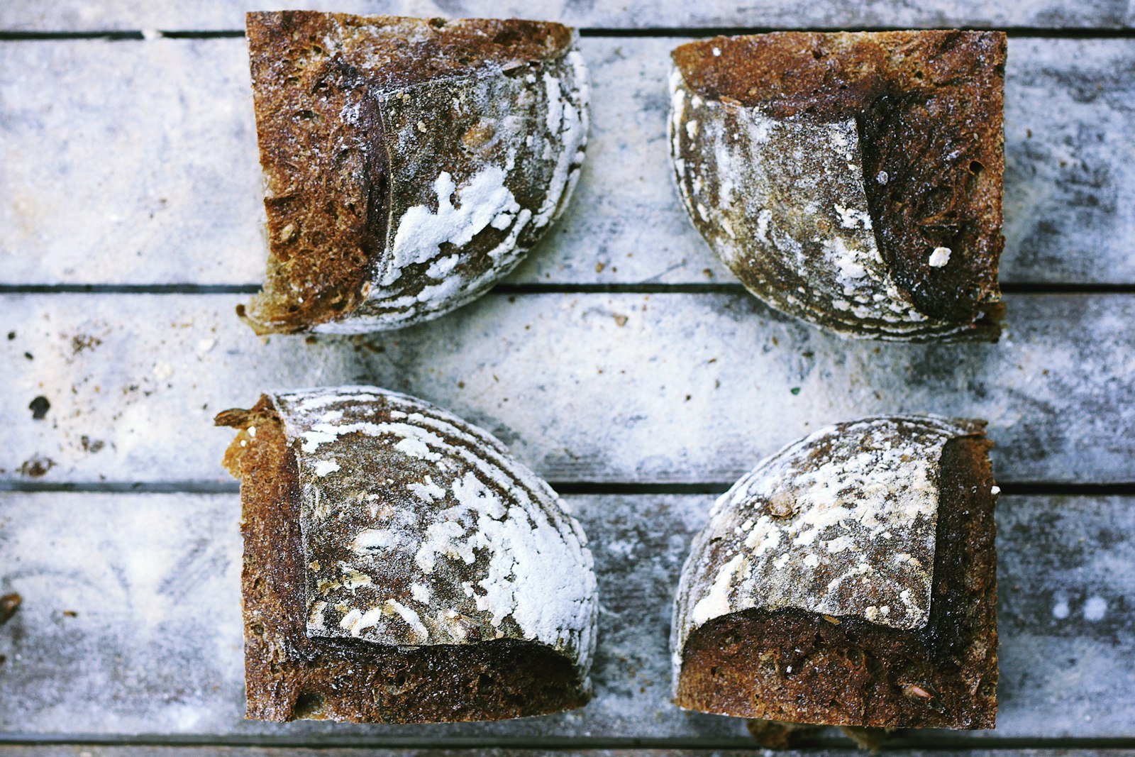 A spatula spreading fluffy cream cheese frosting over a pan of golden brown gingerbread bars, with ground cinnamon and a whisk nearby