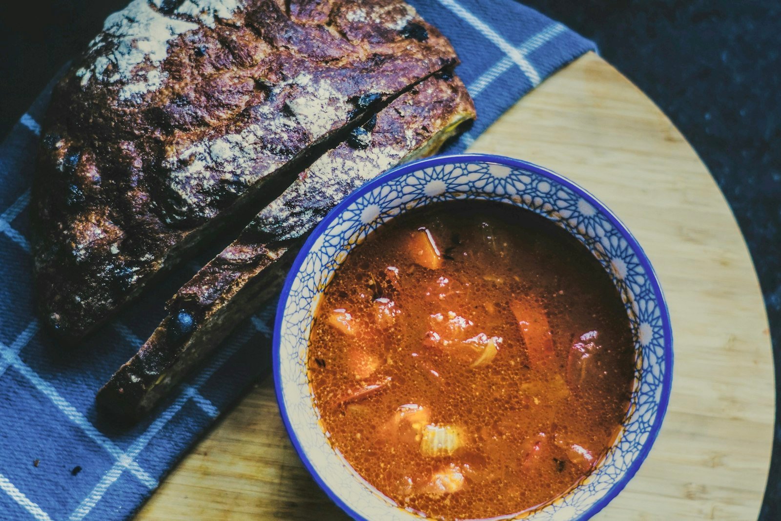 A rustic bowl of thick ham and bean soup with creamy navy beans, diced ham, carrots and celery, garnished with parsley and served with a slice of crusty bread