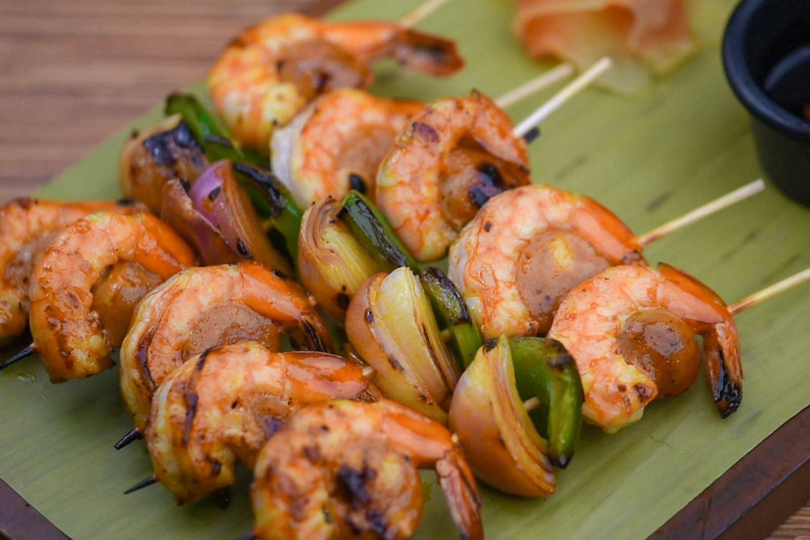 Honey garlic shrimp skewers being brushed with a sticky glaze right after coming off the grill