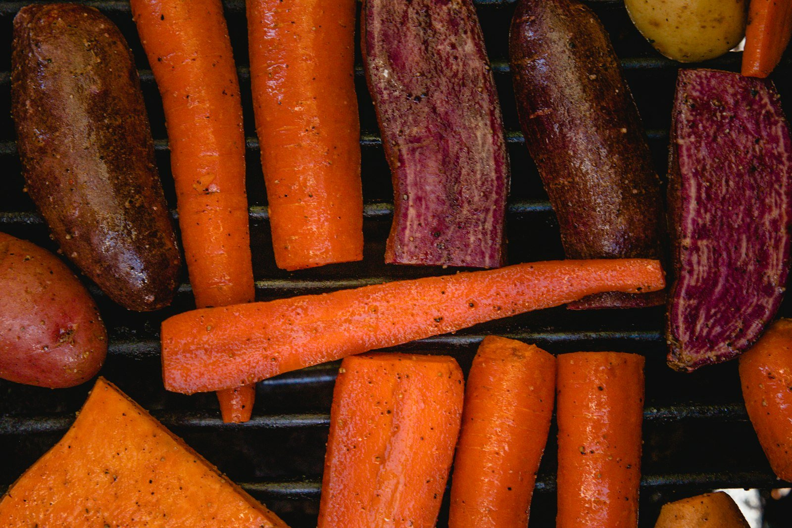 Overhead view of a sheet pan of maple glazed root vegetables fresh from the oven, with caramelized carrots, parsnips, sweet potato and onion wedges and thyme sprigs