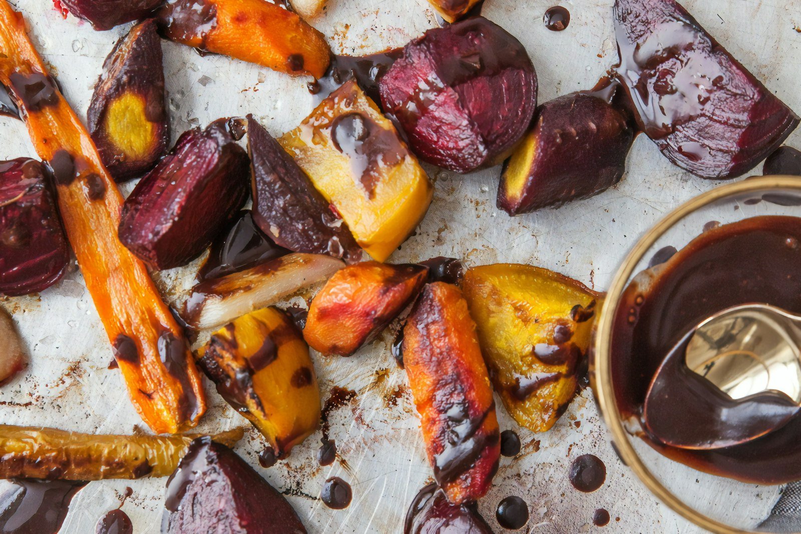 A platter of maple roasted root vegetables with caramelized carrots, parsnips, sweet potatoes and red onion, glossy with glaze and sprinkled with fresh thyme