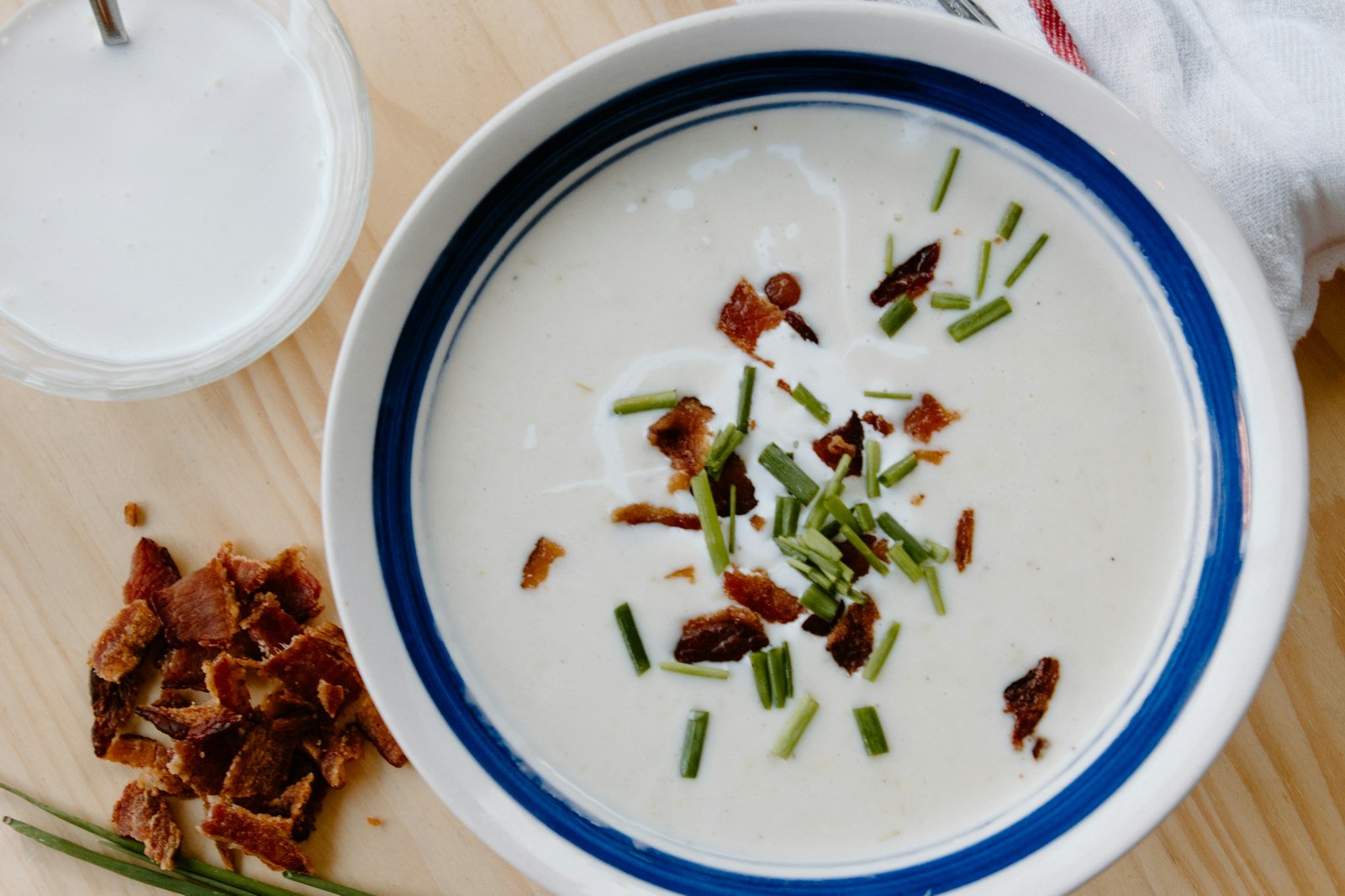 A bowl of creamy New England clam chowder with bacon, chives and oyster crackers