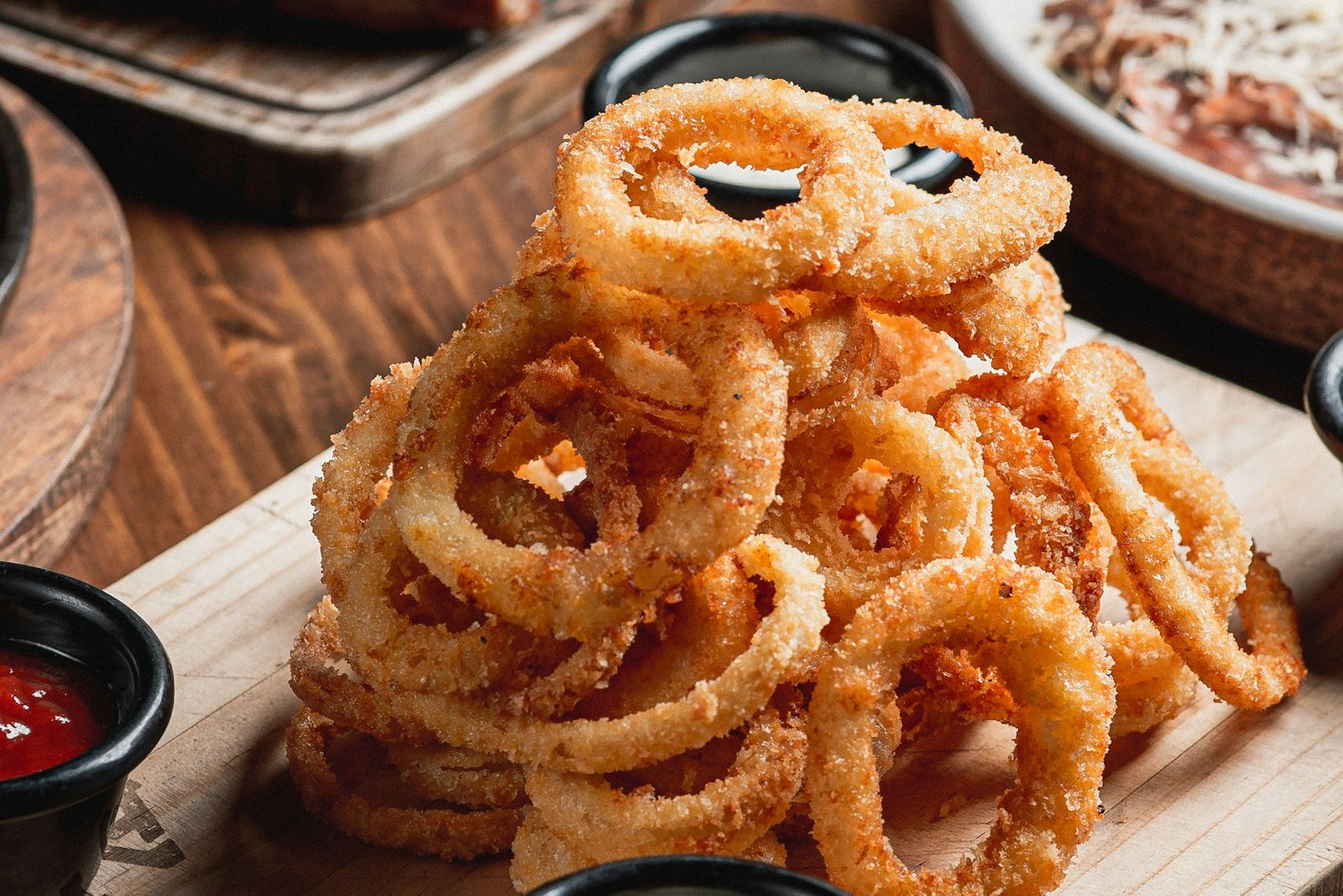 Golden parmesan onion ring chips on a parchment-lined baking sheet with lacy cheese edges and a bowl of ranch dip
