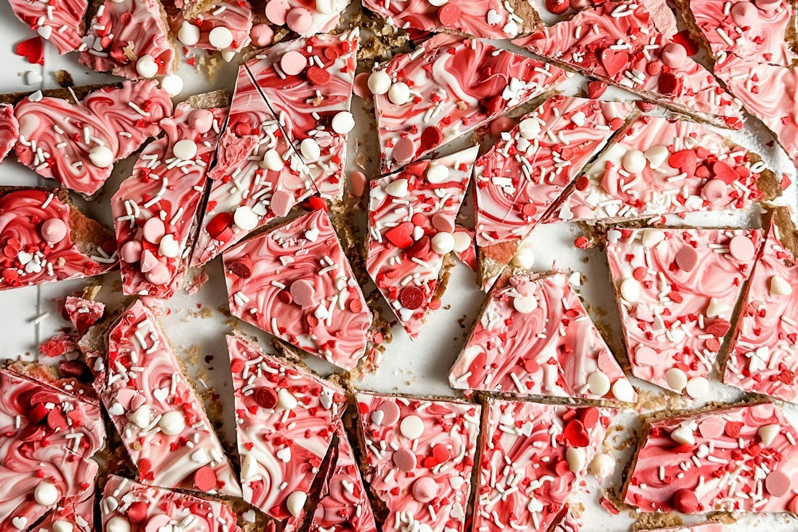 Squares of layered dark and white chocolate peppermint bark topped with crushed candy canes on a holiday tray