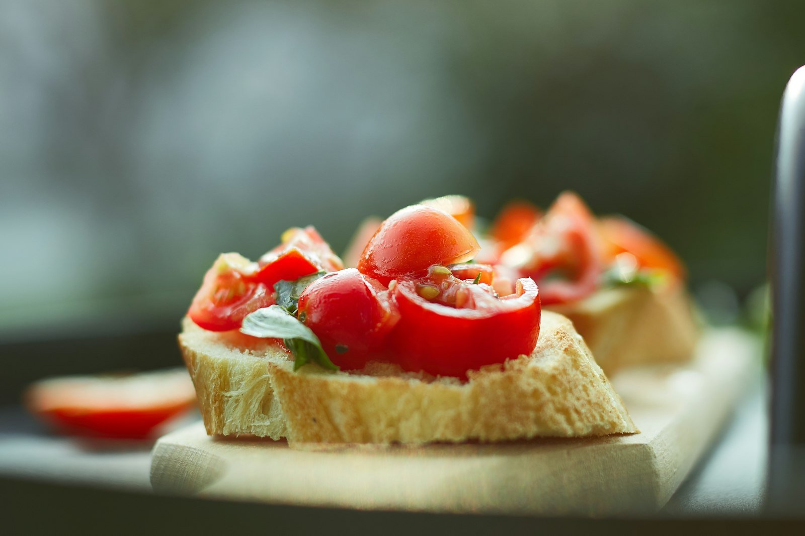 Crostini lined up on parchment with creamy goat cheese, ruffled prosciutto, fresh fig slices and a honey drizzle