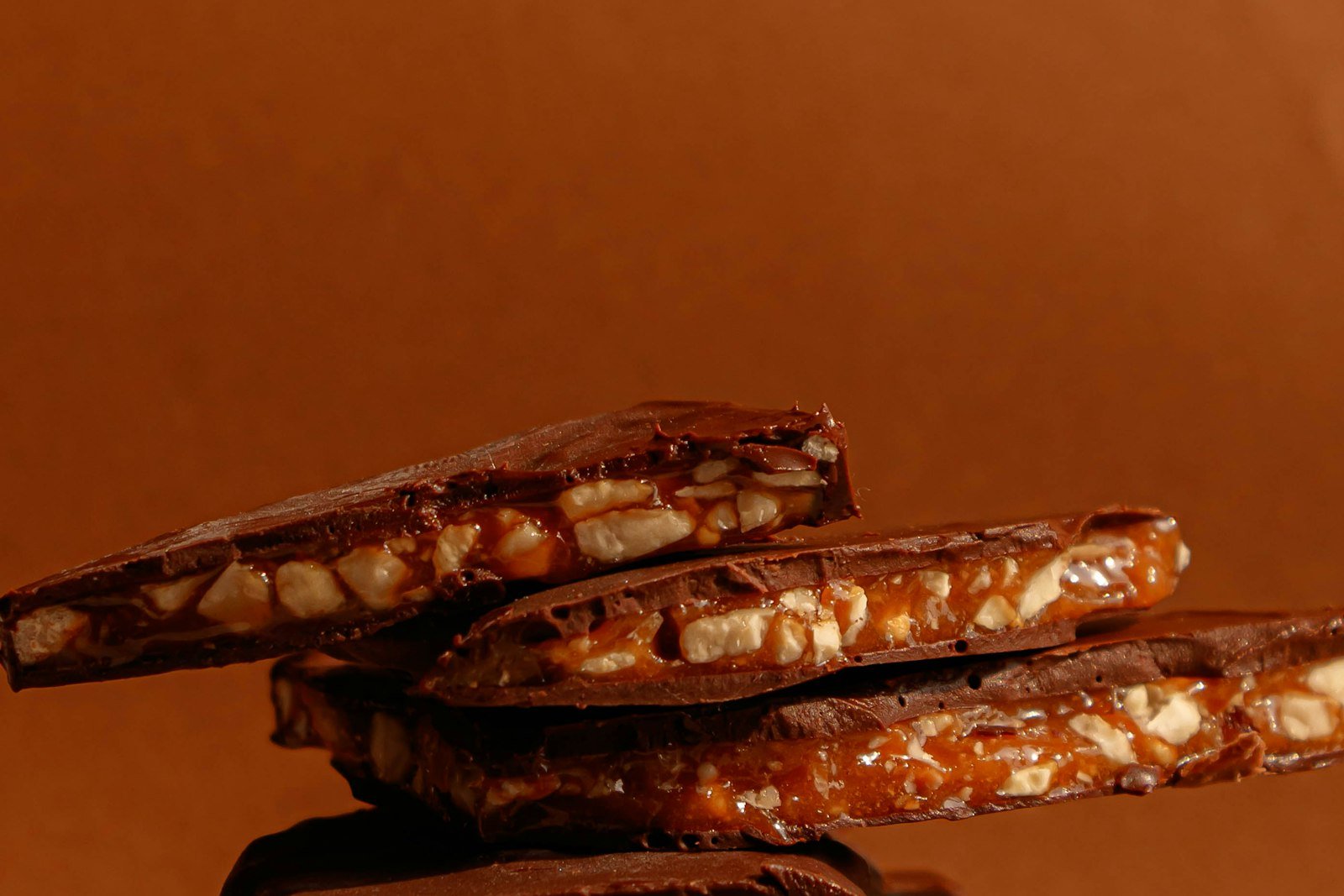 Pressing a toasted pecan half into a softened chocolate caramel candy on a waffle pretzel