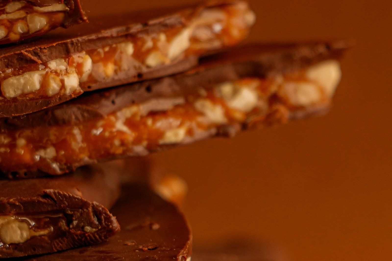 Salted caramel chocolate pretzel bites topped with pecans and flaky sea salt on a parchment-lined tray