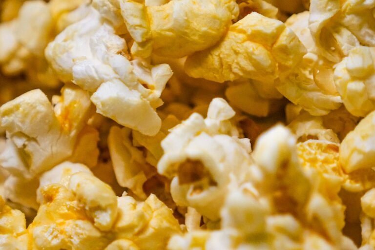 A big rimmed baking sheet piled with glossy golden salted caramel popcorn, with a few clusters broken apart