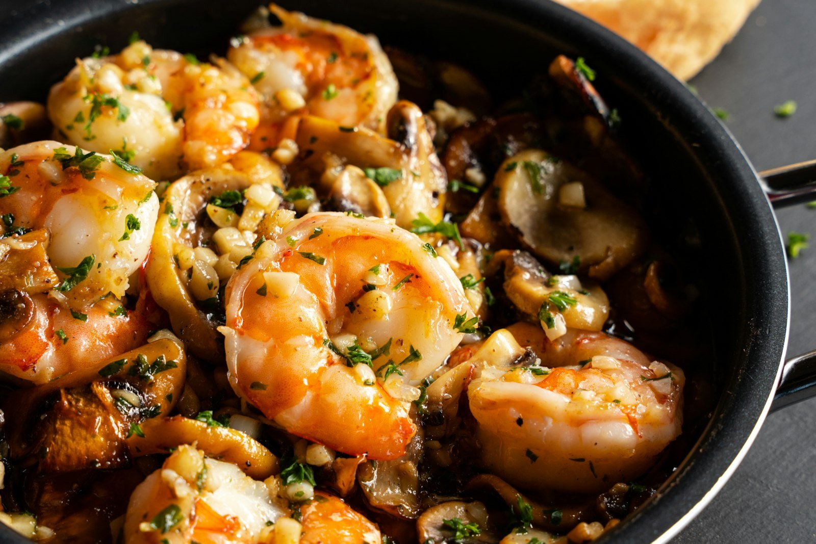 A baking dish of shrimp oreganata with jumbo shrimp under golden oregano breadcrumbs, lemon wedges and chopped parsley