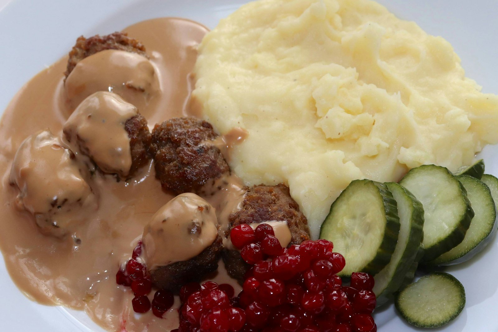 A skillet of golden Swedish meatballs in creamy brown gravy, sprinkled with fresh parsley