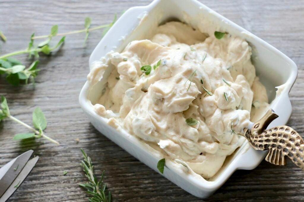 A shallow bowl of whipped feta swirled with hot honey, surrounded by warm pita wedges and crisp vegetables